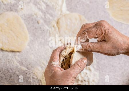 Großmutter Bäckerhände machen Kuchen aus Teig. Hausgemachte Küche. Prozess der Tortenherstellung, Hand. Hands Pie Teig. Teig zum Backen, Teigstücke. Frauen Stockfoto