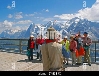 Mann, der japanische Touristen auf der Aussichtsplattform am Bahnhof Birg auf dem Weg nach Schilthorn/Piz Gloria, Jungfrau Region, Kanton Berner Schweiz fotografiert Stockfoto