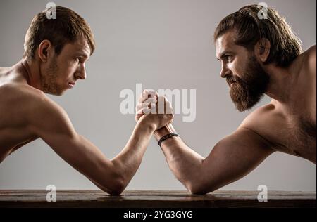 Zwei Männerhände umklammten Arm Wrestling, stark und schwach, ungleiche Übereinstimmung. Stark muskulös bärtigen Mann Arm Ringen ein mickrigen schwachen Mann Stockfoto