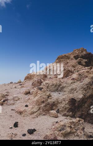 Eine markante Felsformation aus Teide, die in warmen Orangetönen getaucht ist, vor einem leuchtend blauen Himmel. Dieser dramatische Kontrast fängt die einzigartige Schönheit Tenerifs ein Stockfoto