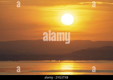 Sonnenuntergang über einem ruhigen Meer mit Bergen im Hintergrund, Hegne, Allensbach, Bodensee, Baden-Wuerttemberg, Deutschland, Europa Stockfoto