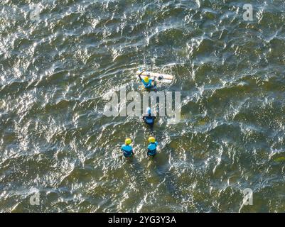 Menschen schwimmen auf dem Meer auf einem Kiteboard oder Kitesurfen. Sommersport beim Kitesurfen. Kitesurfunterricht in der Bucht. Kitesurfen in der Bucht. Stockfoto