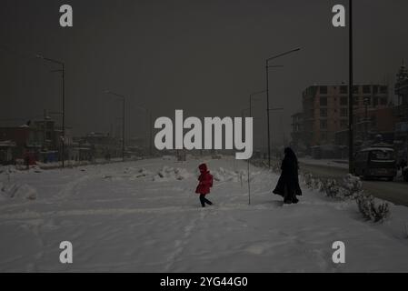 Eine Mutter mit ihrer Tochter geht an einem stark verschmutzten Morgen in Kabul, Afghanistan, am 4. Februar 2020 durch ein schneebedecktes Gebiet der Stadt. Die Stockfoto