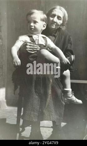 Jugoslawien - 1920er Jahre: Schwarz-weißes Porträt eines kleinen Jungen, der auf dem Schoß seiner Großmutter sitzt Stockfoto