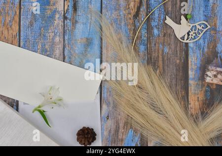 Boho, Weihnachtsdekoration und leeres Blatt Papier und Umschlag zum Füllen mit Inhalt auf blauen Holztafeln, dekoriert mit Blumen, Gras... Stockfoto