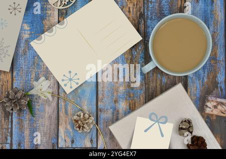 Foto gemischt mit Grafiken: Leere Weihnachtskarte zum Füllen mit Inhalt, Geschenk, weißer Kaffee in einer Tasse, Kegel auf blauem Holzhintergrund, Ansicht von oben. Stockfoto