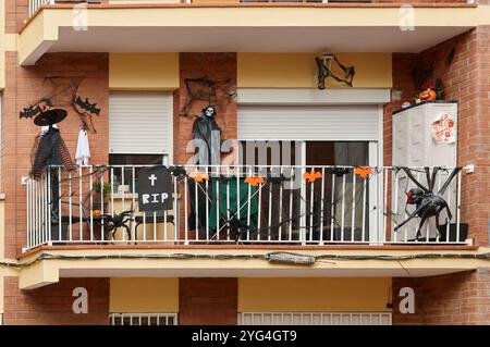 Ein Appartement-Balkon, dekoriert für Halloween mit verschiedenen gruseligen Elementen, darunter ein Skelett, Fledermäuse, Spinnen und ein Rip-Schild, schaffen ein festliches und Stockfoto