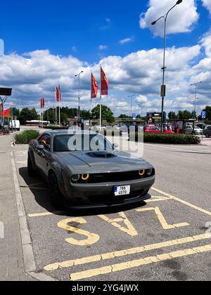 Brünn, Tschechische Republik - 22. Mai 2022: In einem sonnigen Einkaufszentrum parkt ein eleganter grauer Muscle Car Dodge Challenger R/T 5,7. Helle Fahnen und eine blaue Ske Stockfoto