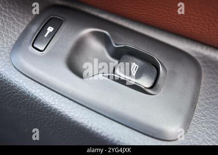 Moderne Nahaufnahme des Innenraums. Fahrertürbedienkonsole in Armlehne mit Fensterbedienkonsole, Verriegelungstaste. Stockfoto