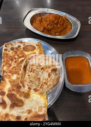 Food-Shot-Präsentation mit reinem und Ei Roti Prata, einem Teller mit Fisch-Curry, einem Teller mit Masala-Huhn in normaler Größe zum Abendessen. Singapur. Stockfoto