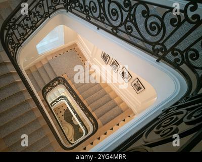 Eine elegante Treppe ist in der La Galerie Dior hervorgehoben, mit komplizierten Eisengeländern und sanfter Beleuchtung, die das stilvolle Design und die dezente Beleuchtung beleuchtet Stockfoto