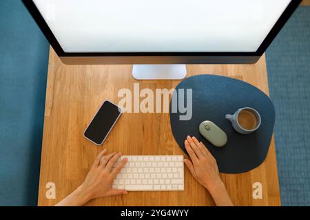 Zugeschnittene Hände am Tisch mit dem Computer Stockfoto