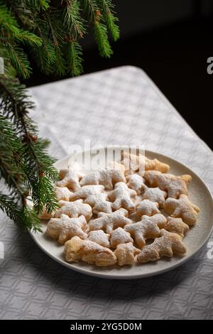 Ein Teller mit weihnachtlichen Dessertkeksen mit weißem Puderzucker drauf. Die Kekse sind wie Weihnachtsbäume und andere Figuren geformt Stockfoto