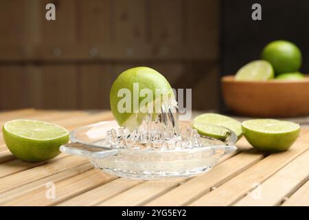 Glas Entsafter und frische Limetten auf Holztisch, Nahaufnahme Stockfoto