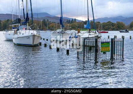 Vertäute Yachten haben sich in der Nähe eines Anlegesteges am Lake Windermere festgebunden, der aufgrund der jüngsten starken Regenfälle im englischen Lake District überschwemmt wurde Stockfoto