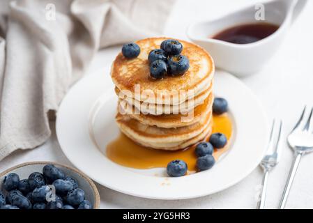 Frühstück Buttermilchpfannkuchen mit Heidelbeeren und Ahornsirup auf weißem Teller, Nahansicht Stockfoto