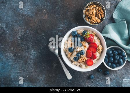 Haferbrei Schüssel mit Beeren und Walnüssen auf blauem Hintergrund. Kopierbereich in der Draufsicht. Konzept des sauberen Essens, der Diät Stockfoto