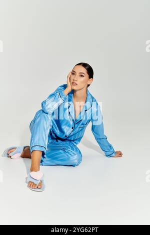 Eine modische junge Frau sitzt nachdenklich in moderner Loungewear, die Selbstvertrauen und Stil ausstrahlt. Stockfoto