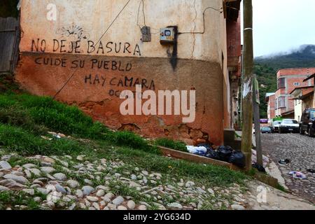 Müll wurde zur Abholung an der Straßenecke neben Grafitti hinterlassen und die Leute gebeten, sich um das Dorf zu kümmern und ihren Müll nicht draußen auf der Straße zu lassen, Coroico, Yungas Region, Bolivien Stockfoto