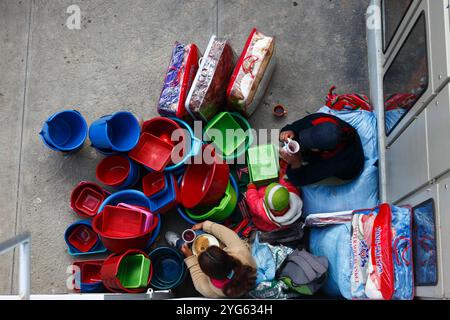 Blick von oben mit Blick auf die junge Familie, die Plastikschüsseln, Eimer und Decken auf dem Straßenmarkt, Coroico, Yungas Region, Bolivien verkauft Stockfoto