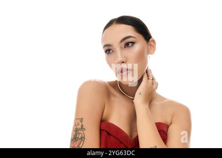 Eine junge, schöne Frau zeigt ihre Eleganz, trägt ein rotes Kleid und zeigt eine nachdenkliche Pose. Stockfoto