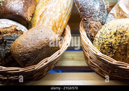 Verschiedene Arten von frischem Brot im Korb im Regal in der Bäckerei. Stockfoto