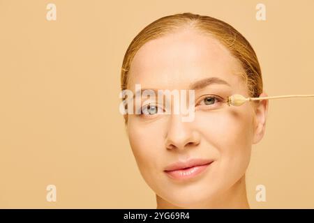 Eine junge, schöne Frau in Übergröße wendet sanft Hautpflege auf ihr Gesicht an und zeigt Selbstpflege. Stockfoto