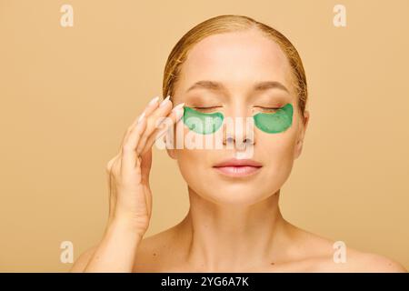 Eine junge Frau in Übergröße genießt Selbstpflege, indem sie grüne Flecken unter ihren Augen aufträgt. Stockfoto