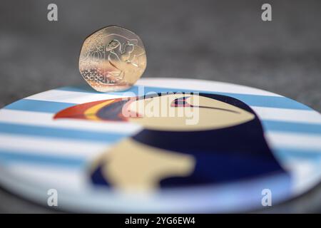 Ein 20-Pence-Stück mit einem Papageientaucher, der auf einer blau-weiß gestreiften Achterbahn sitzt, auf der ein Papageientaucher steht Stockfoto