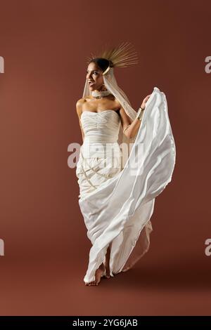 Eine atemberaubende afroamerikanische Frau in einem fließenden weißen Kleid und einer Perlenkette strahlt Eleganz in einem Studio aus. Stockfoto