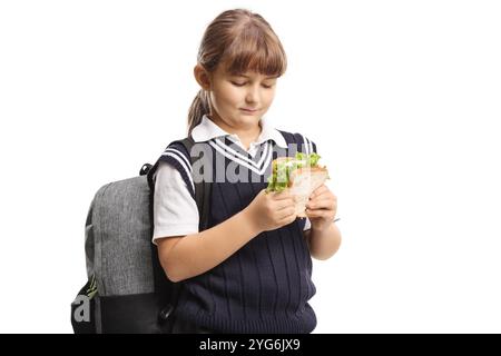 Schulmädchen mit einem Rucksack, der ein Sandwich auf weißem Hintergrund hält Stockfoto