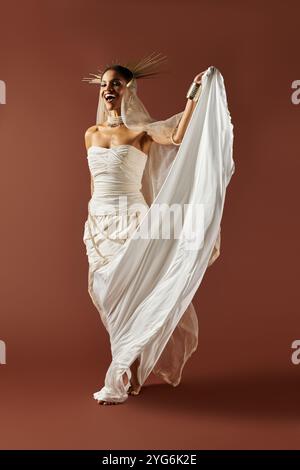 Eine elegante afroamerikanische Frau zeigt Anmut in einem weißen Kleid und einer Perlenkette vor braunem Hintergrund. Stockfoto