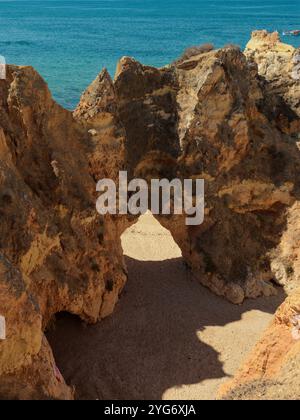 Der natürliche Felsbogen führt nach praia da rocha, der von Sonnenlicht umgeben ist und von lebhaften Blautönen des Ozeans umgeben ist Stockfoto