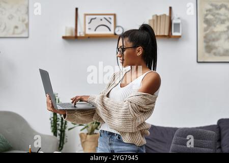 Die Frau nimmt ihren Laptop in Anspruch und genießt eine produktive Lerneinheit in ihrem stilvollen Zuhause. Stockfoto