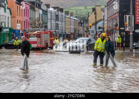Ein Feuerwehrmann begleitet eine Frau bei Überschwemmungen in Bantry, West Cork, Irland. Stockfoto