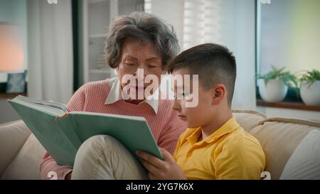 Liebevolle ältere Frau pensionierte Großmutter liest Buch mit Enkel zu Hause auf dem Sofa und genießt interessante Märchengeschichte liebevolle Oma hilft Stockfoto