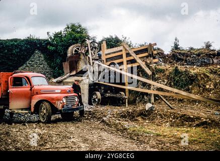 Ein Steinbrecher in Bill Murphys Steinbruch in Castleisland, County Kerry, Irland, aus dem Jahr 1957. Ein alter roter Ford-Lkw ist ebenfalls zu sehen. Stockfoto