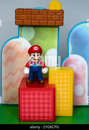 Super Mario steht auf einer roten Plattform mit buntem Hintergrund hinter ihm Stockfoto