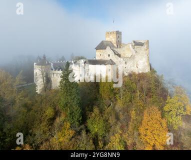 Polen. Mittelalterliche Burg in Niedzica aus dem 14. Jahrhundert (obere Burg) im Herbst im Oktober bei Morgennebel. Bäume in wunderschönen Herbstfarben. Sunris Stockfoto