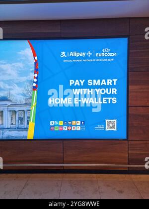 Werbebanner / Display am Flughafen Berlin Brandenburg für Alipay Home E-Wallets während der Euro2024 Stockfoto