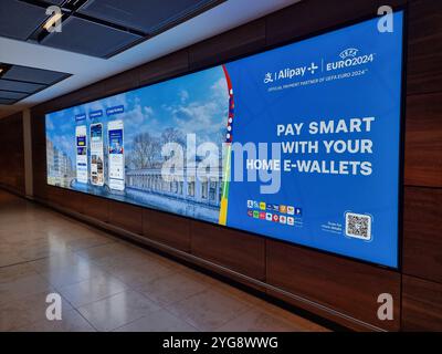 Werbebanner / Display am Flughafen Berlin Brandenburg für Alipay Home E-Wallets während der Euro2024 Stockfoto