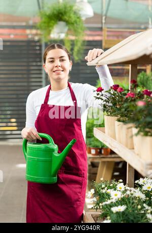 Eine Verkäuferin mit einer Gießkanne im Blumenladen Stockfoto