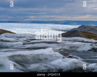 Endmoräne und Vorland des Eisschildes. Braune Sedimente auf dem Eis entstehen durch das schnelle Schmelzen des Eises. Grönland bei Kangerlussuaq. Stockfoto