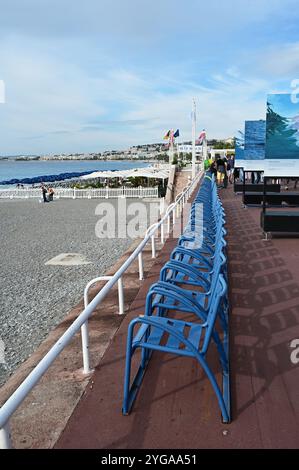 Nizza, Frankreich - 24.09.2024: Reihe blauer Stühle mit Blick auf den Strand an der Promenade des Anglais am sonnigen Sommermorgen. Stockfoto