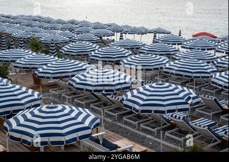 Nizza, Frankreich - 24.09.2024: Auswahl an blauen und weißen Sonnenschirmen am Strand an der Promenade des Anglais am sonnigen Sommermorgen. Stockfoto