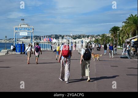 Nizza, Frankreich - 24.09.2024: Leute spazieren auf der Promenade des Anglais neben Strand und Mittelmeer am sonnigen Sommermorgen. Stockfoto
