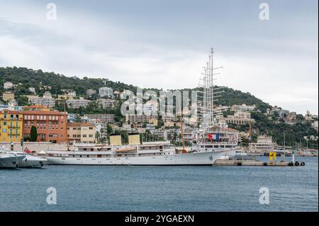 Nizza, Frankreich - 24.09.2024: Kleine Kreuzfahrtschiffe legen im Hafen von Port de Nizza an, mit Wohngebäuden am Hang im Hintergrund. Stockfoto
