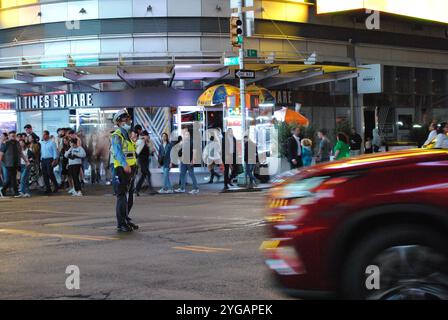 New York City, New York, USA - 6. November 2024: Offizier, der den Verkehr an der Kreuzung von 42nd Street und 8th Avenue in Manhattan leitet. Stockfoto