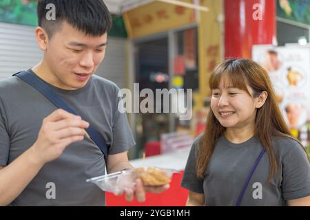 Chinesisches malaysisches Paar in den 30ern kaufte und aß Kinako Mochi Dessert im Shop im chinesischen Tempel in Kuala Lumpur, Malaysia. Stockfoto