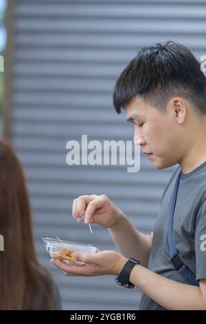 Chinesisches malaysisches Paar in den 30ern kaufte und aß Kinako Mochi Dessert im Shop im chinesischen Tempel in Kuala Lumpur, Malaysia. Stockfoto
